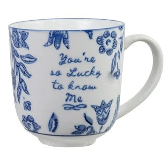 A white ceramic mug with a blue floral pattern and the handwritten text 'You're so lucky to know me' on the side, set against a plain white background.