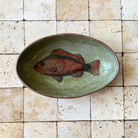 Ceramic plate with a fish design on a tiled wall